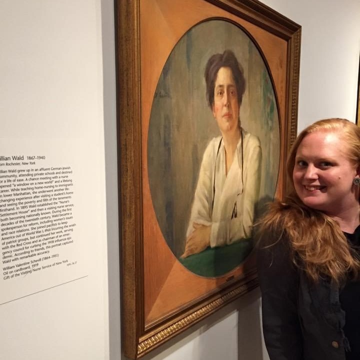 Image of Audrey Hopper in front of a painting, smiling toward camera