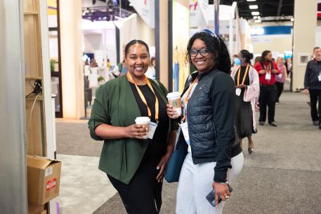 Two African American females smiling with cups of coffee in their hand